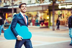 Young businessman walking on the street carrying a big blue cloud